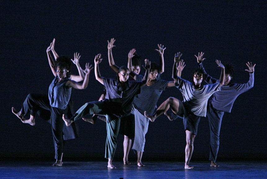Photograph of women dancing with arms upraised.