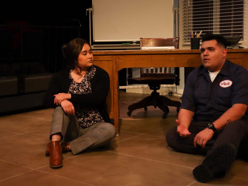 two actors sit on the floor talking intensely in a scene from 'fade'