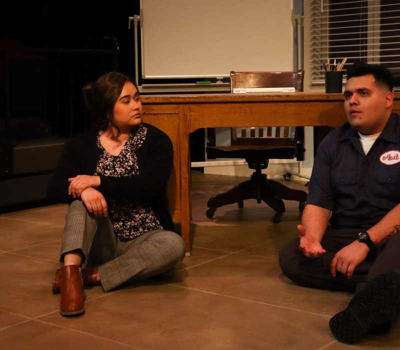 two actors sit on the floor talking intensely in a scene from 'fade'