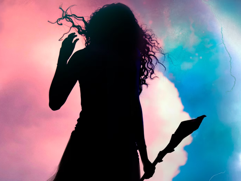 Prospera in silhouette stands facting a storm with her magical staff in hand